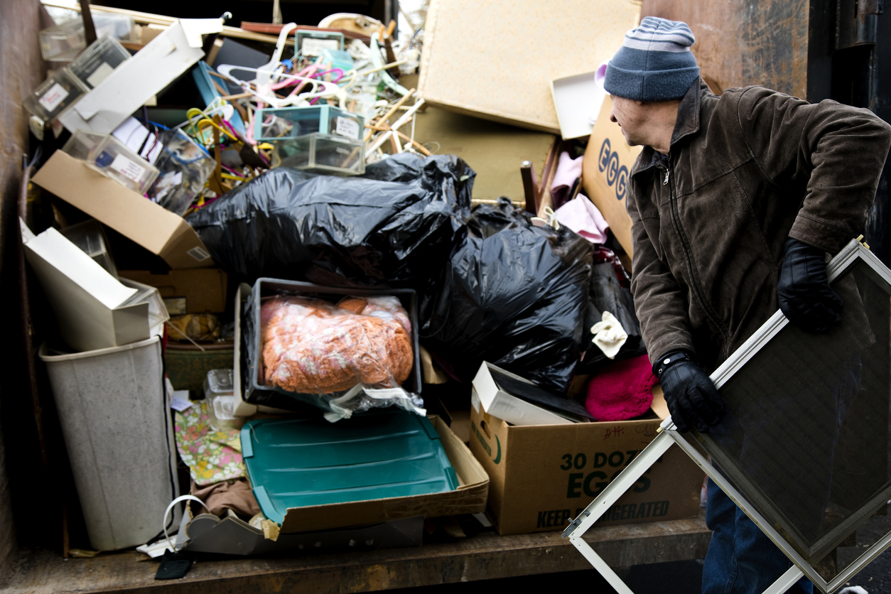 Workman loading junk in dumpster